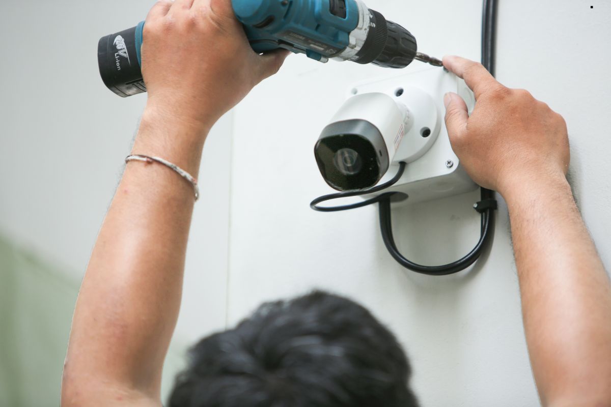 A person drills into a wall to install a camera for home security purposes, enhancing safety and surveillance.