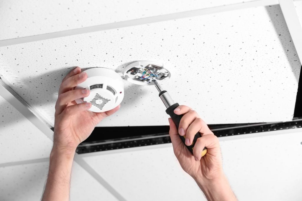 A person is repairing a ceiling fan using a screwdriver, focused on the task at hand.